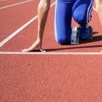 Athlete in starting blocks poised for a sprint on an outdoor track.