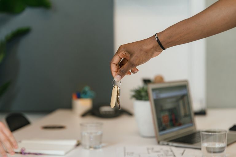 Close-up of a handshake exchanging keys in an office setting.