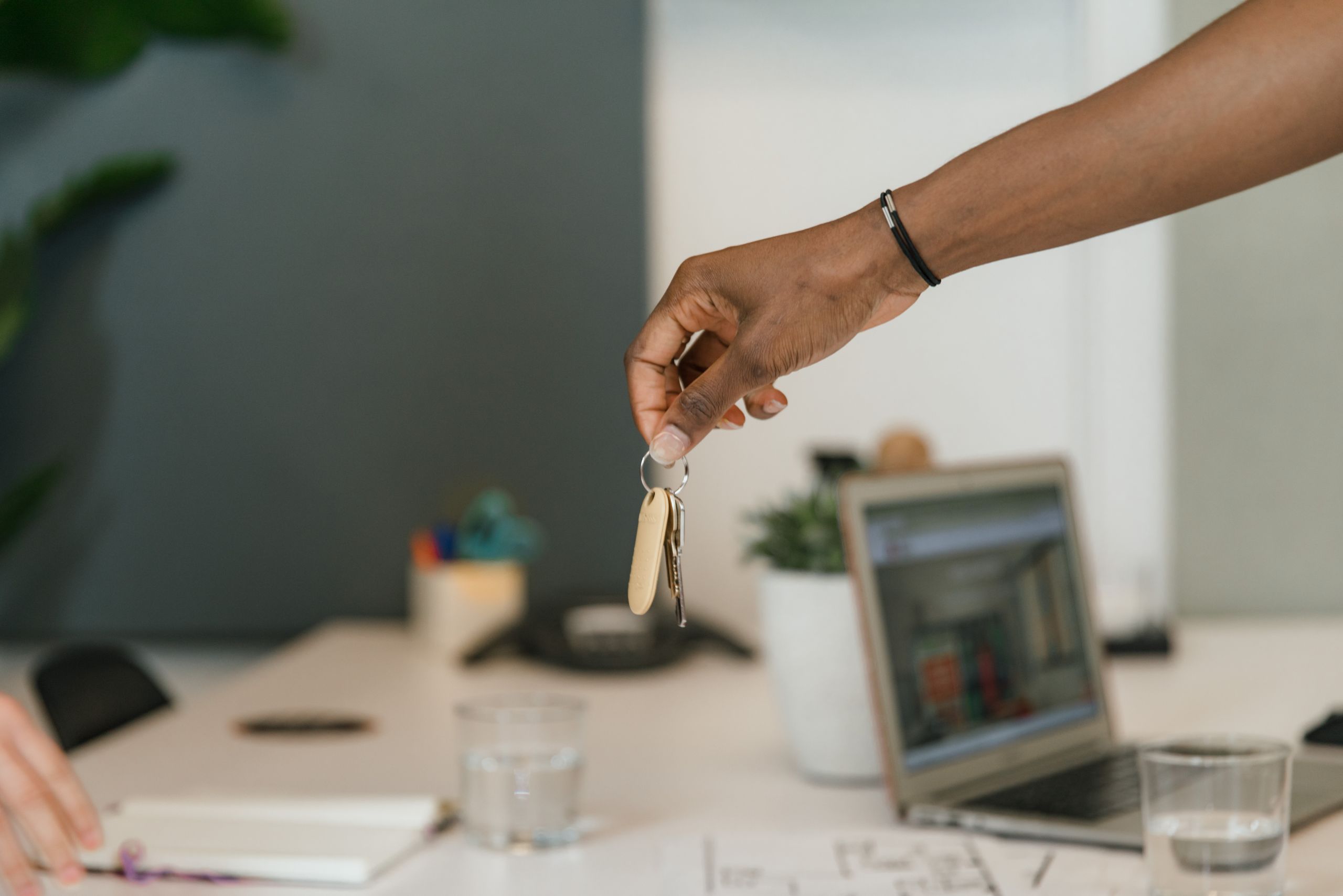 Close-up of a handshake exchanging keys in an office setting.