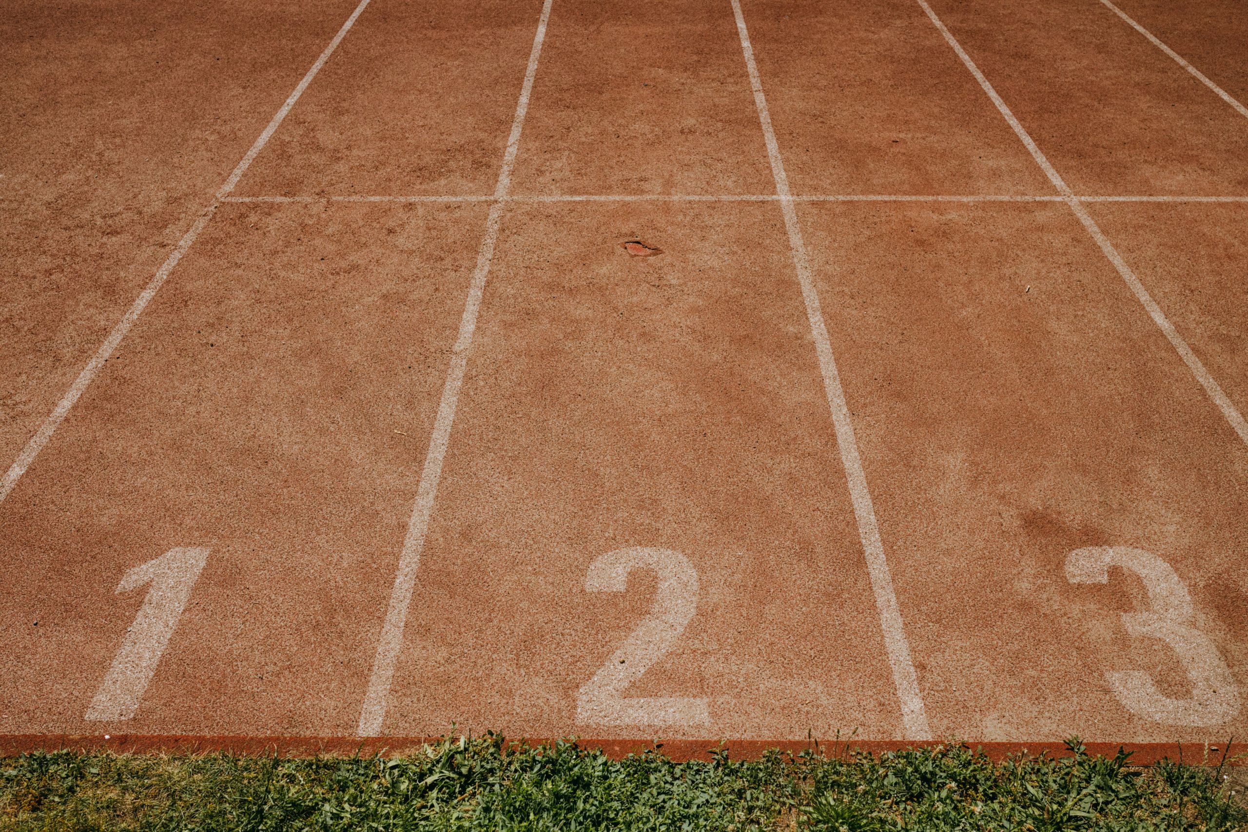 Top view of an athletics track featuring lanes marked with numbers 1, 2, and 3.