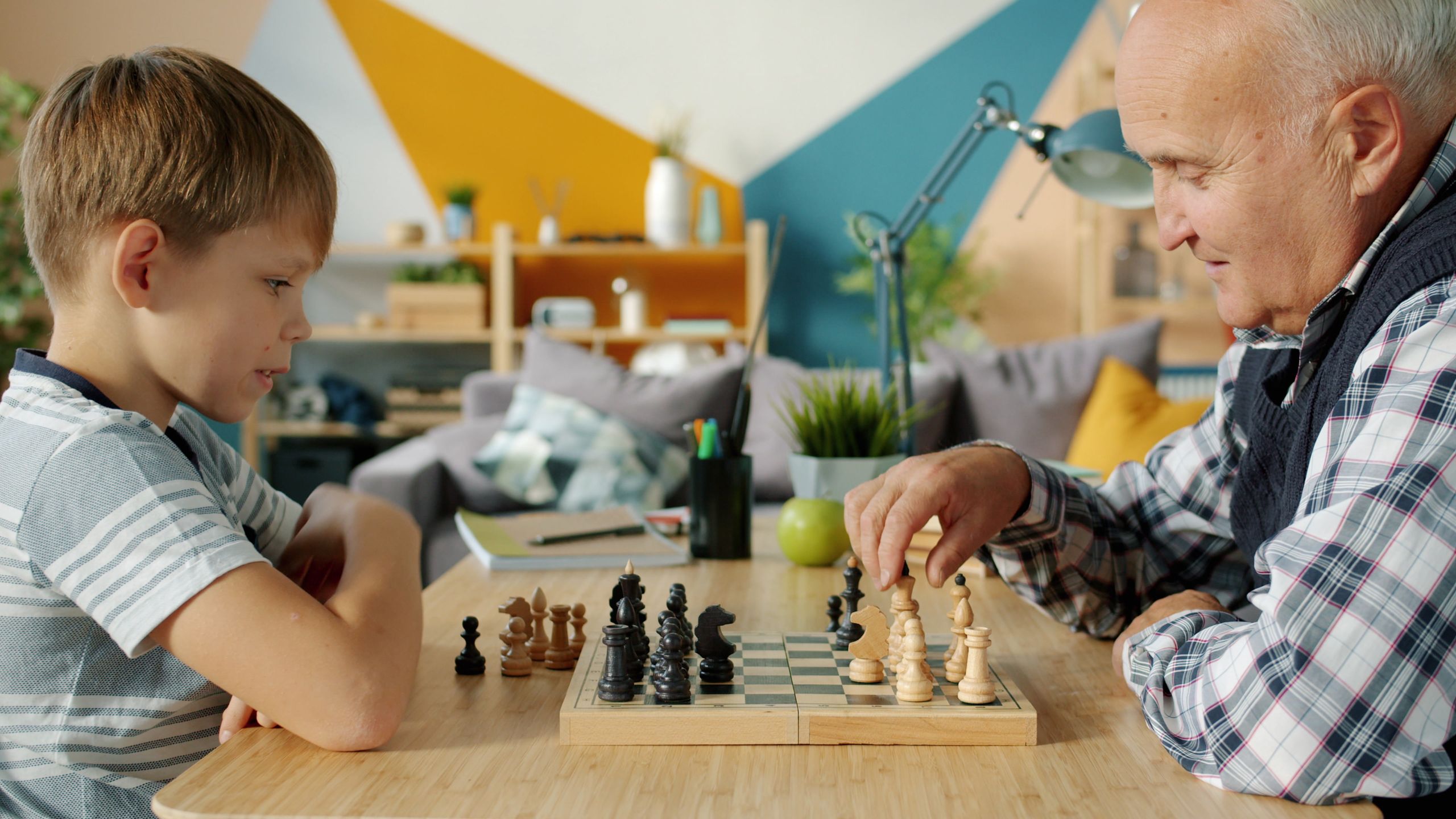A grandfather and grandson engaged in a thoughtful game of chess in a cozy living room setting.
