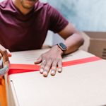 A man applying tape to a cardboard box for moving indoors.