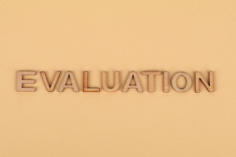 Wooden letter blocks arranged to spell 'evaluation' on a beige background.